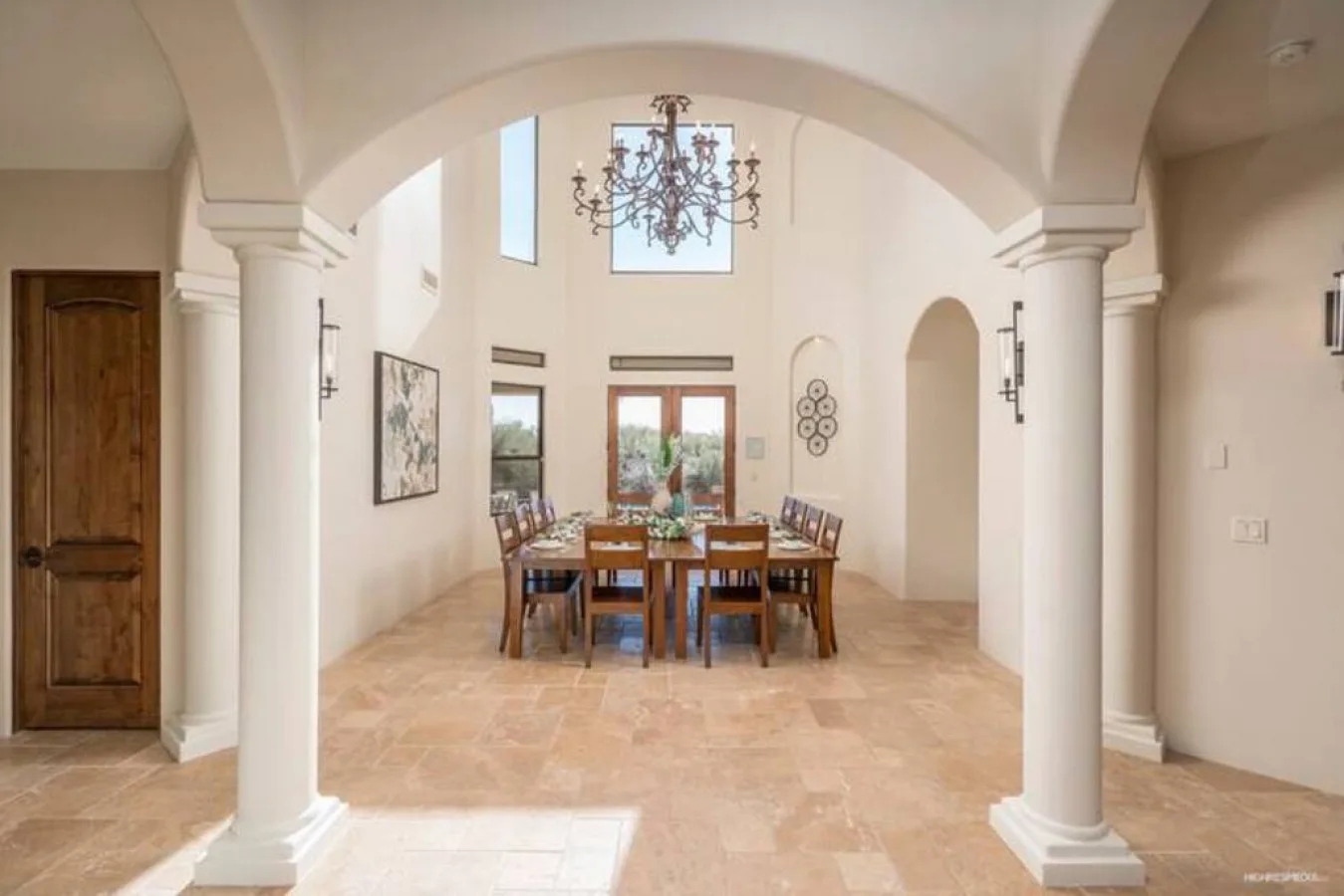 A dining room with a wooden table and chairs beneath arched ceilings.
