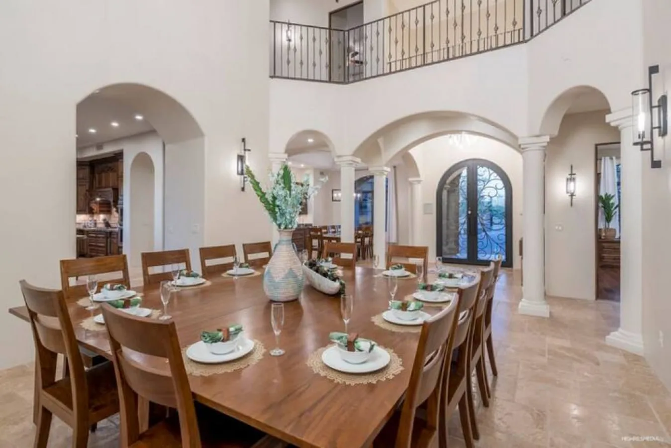 A large dining room with a long wooden table set with place settings.