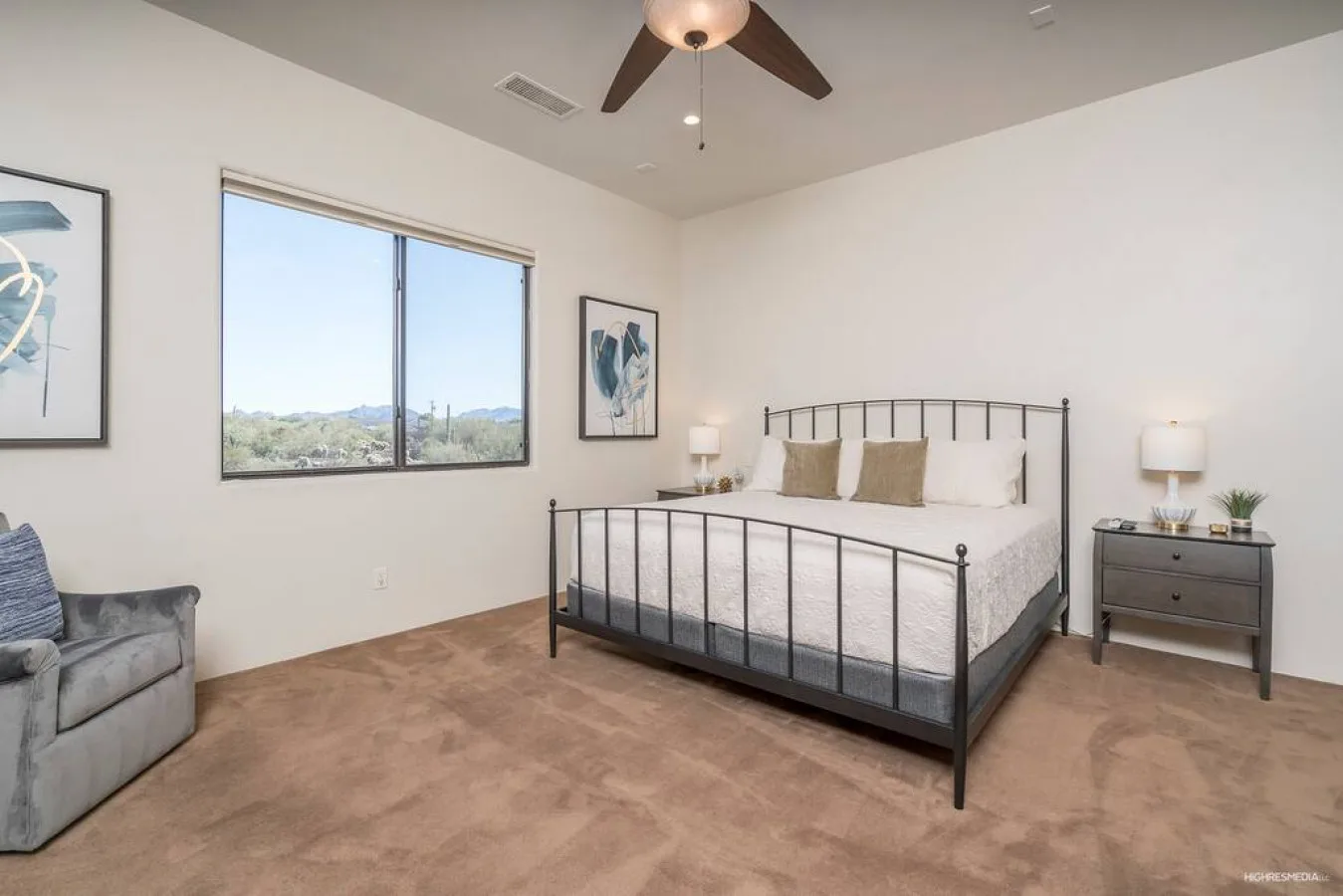 A bedroom with a bed, bedside tables, and a window overlooking the landscape.