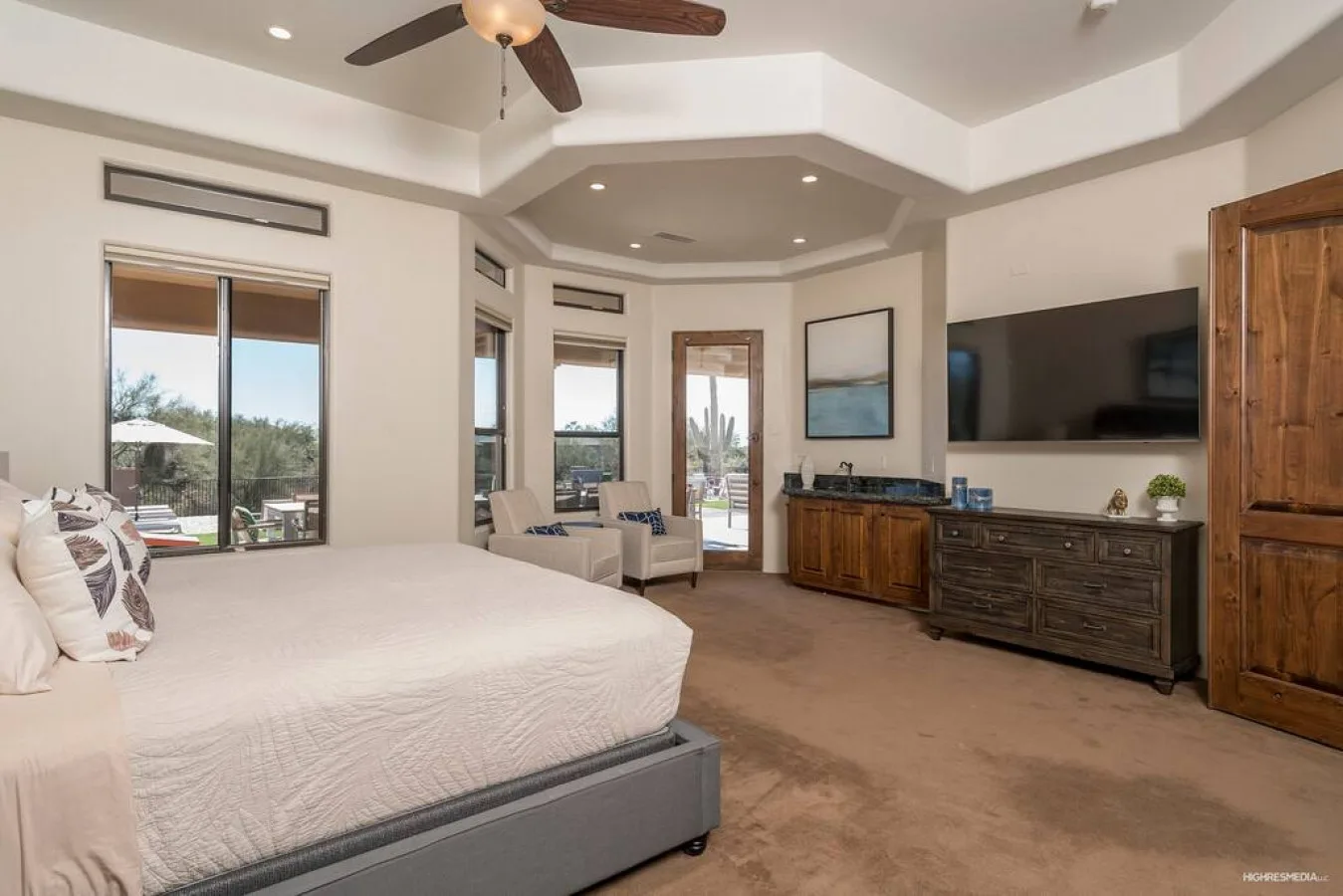 A spacious bedroom with a large bed, seating area, and wall-mounted television.