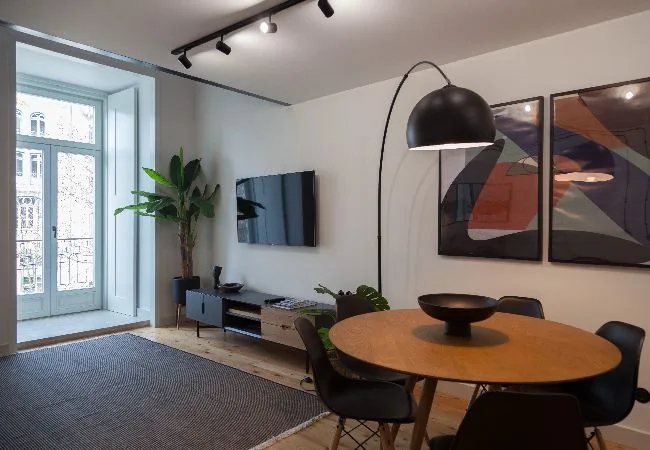 Una sala de estar y comedor con una mesa redonda y un televisor en la pared.
