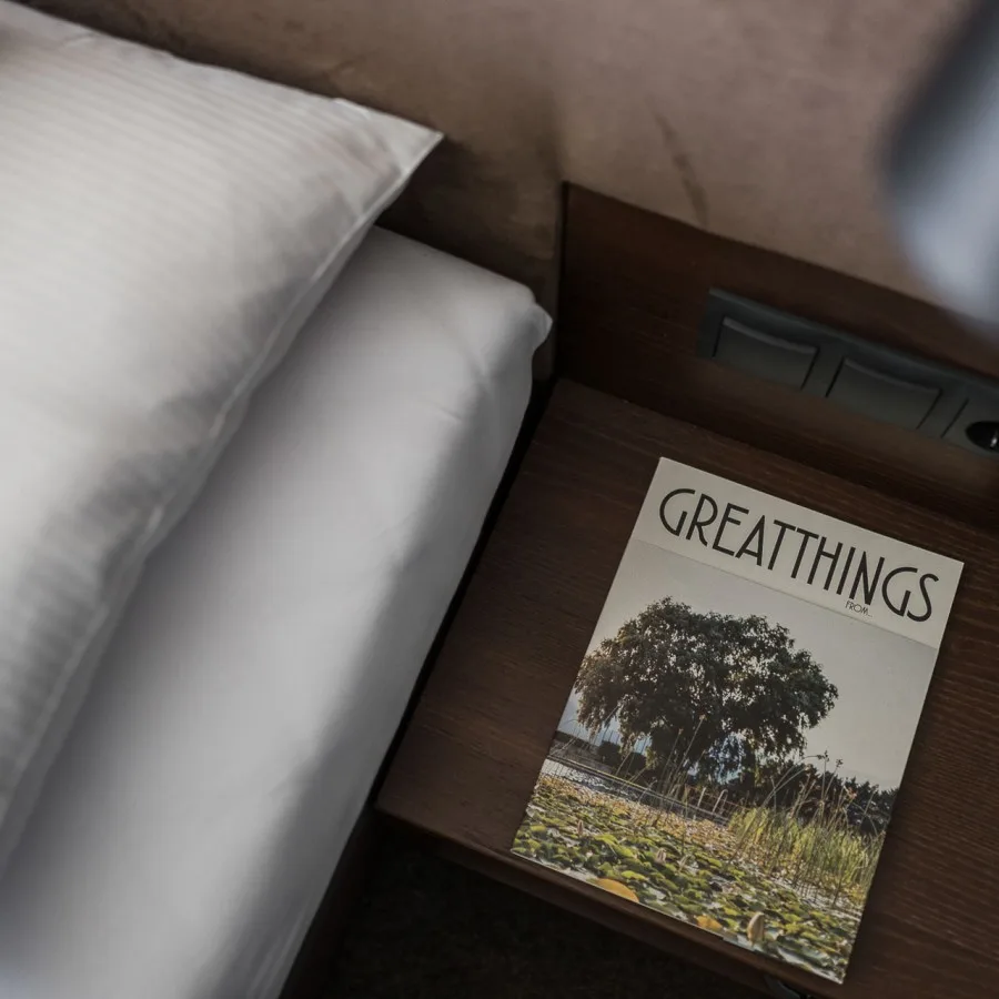 Espacio representativo del hotel: Una cama de hotel junto a una mesa de noche con una revista.