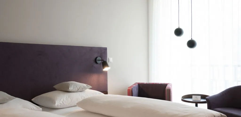 Espacio representativo del hotel: Un dormitorio con cama, cabecero oscuro y lámparas colgantes.