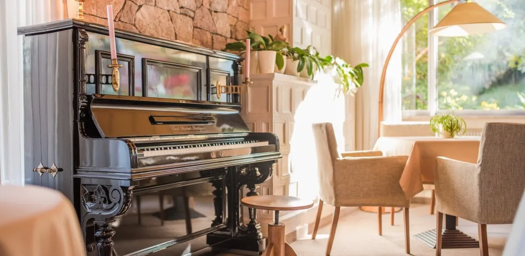 Espacio representativo del hotel: Un comedor luminoso con un piano y asientos tapizados junto a grandes ventanas.