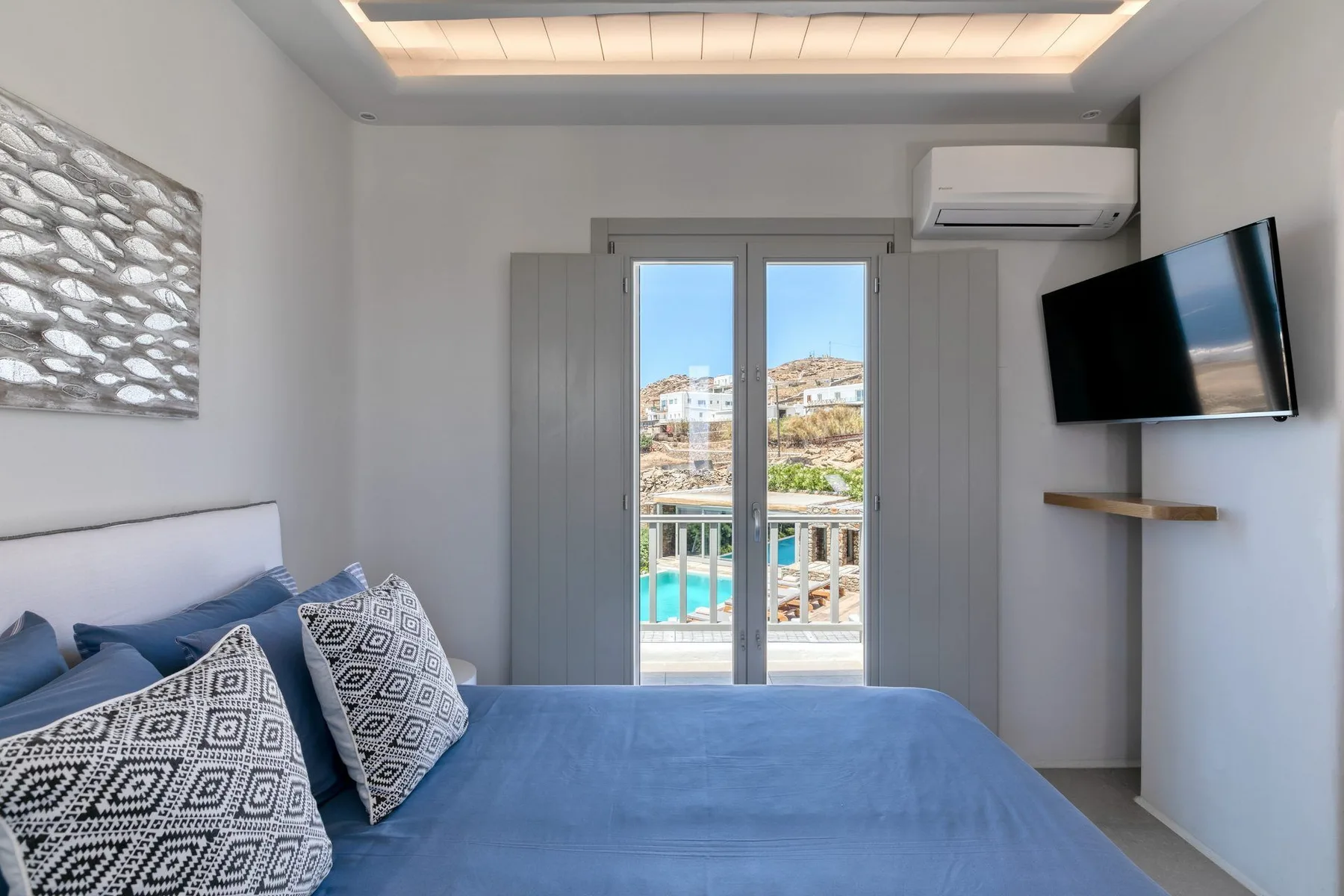 A bedroom with a blue bed and glass doors opening onto a balcony.