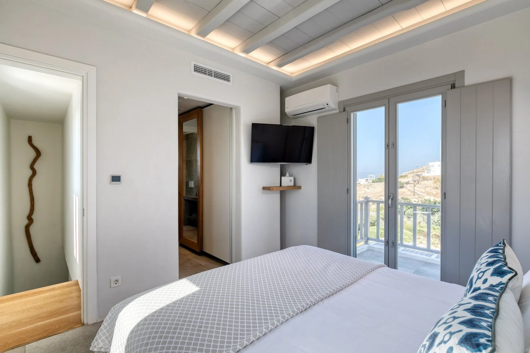 A bedroom with a bed beside glass doors opening onto a balcony.