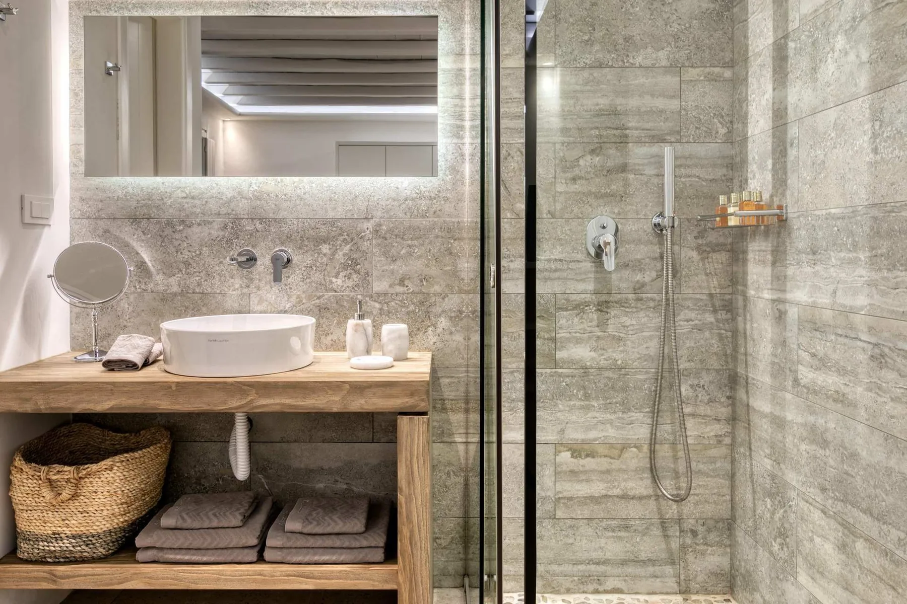A modern bathroom with a wood vanity and a walk-in shower.