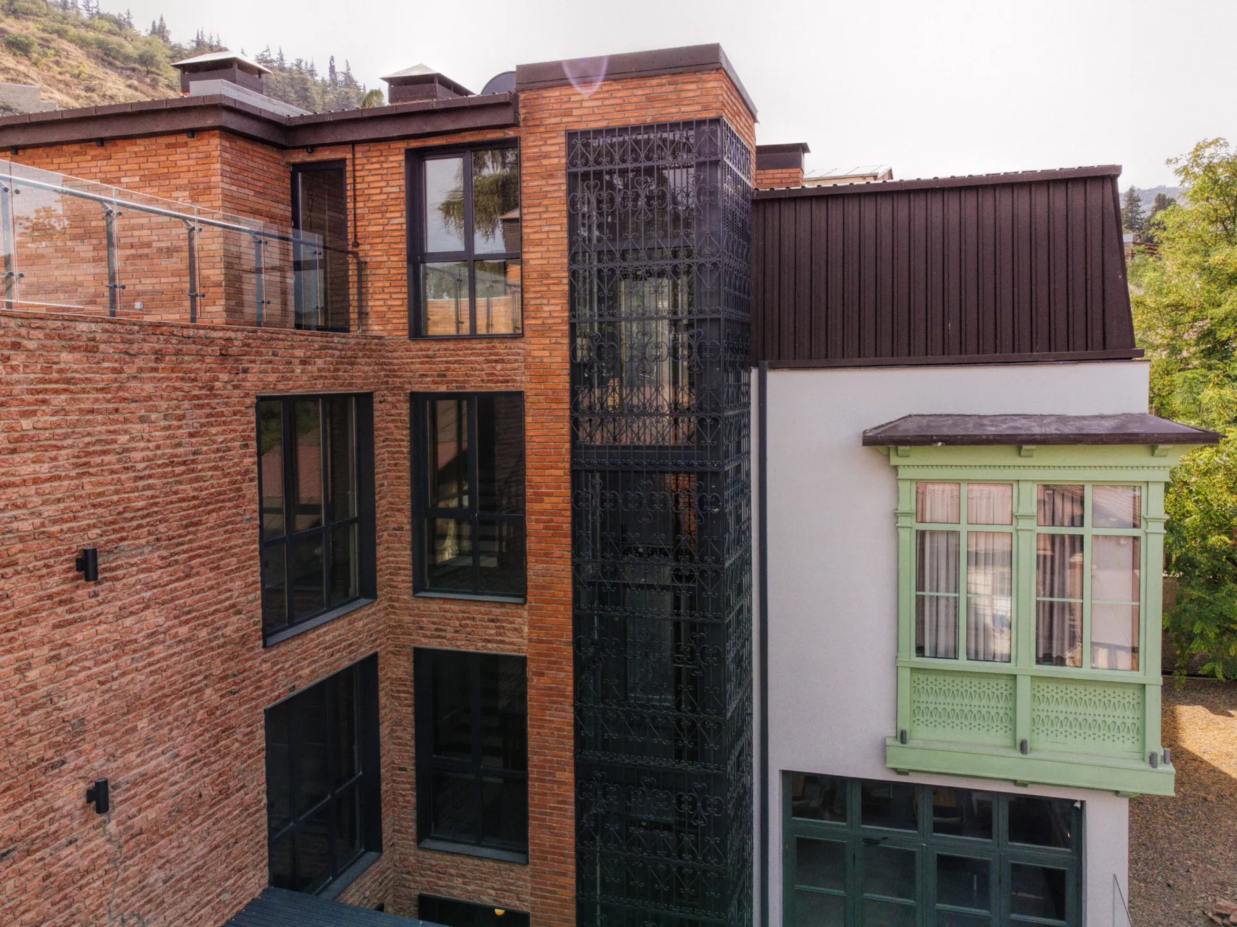 Espacio representativo del hotel: Una fachada de ladrillo presenta ventanas de marcos oscuros y una sección acristalada saliente.