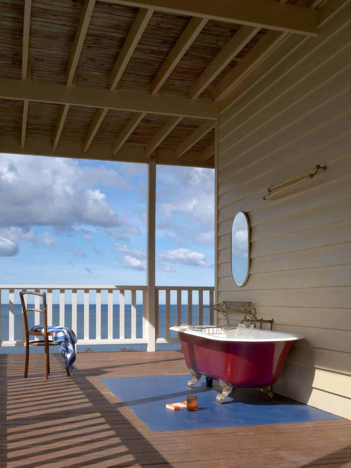 Una bañera exenta está sobre una terraza de madera cubierta con vistas al océano.