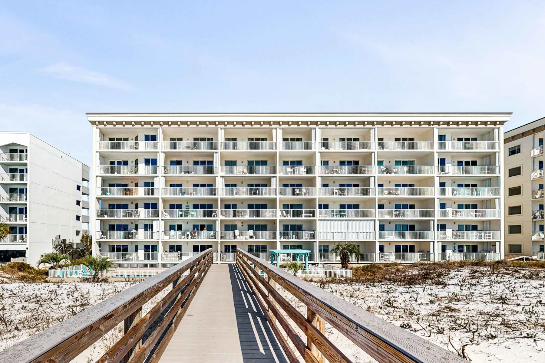 Zona común: Una pasarela elevada conduce hacia un gran edificio junto a la playa.