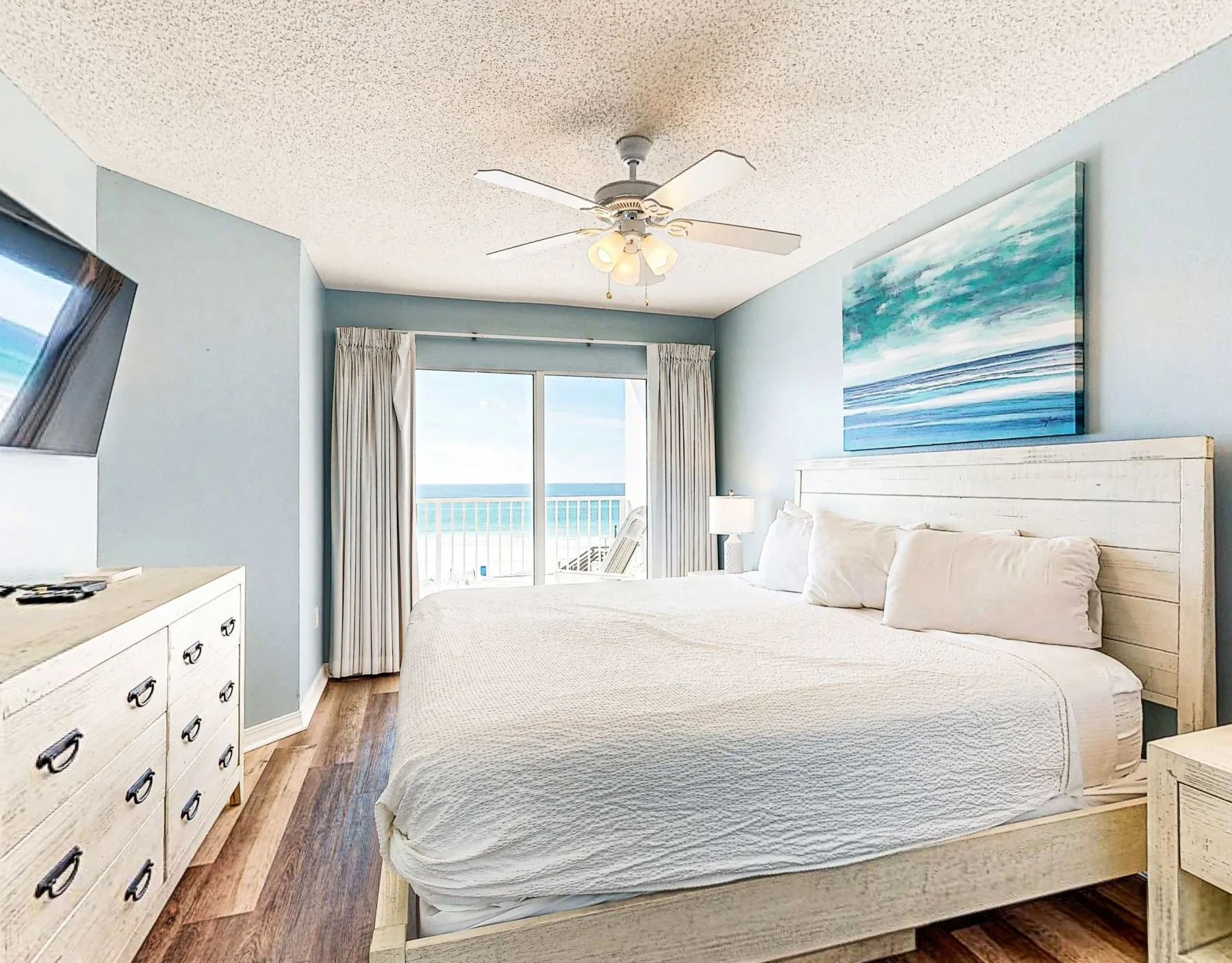 Un dormitorio luminoso con una cama grande junto a puertas corredizas de vidrio con vistas al agua.