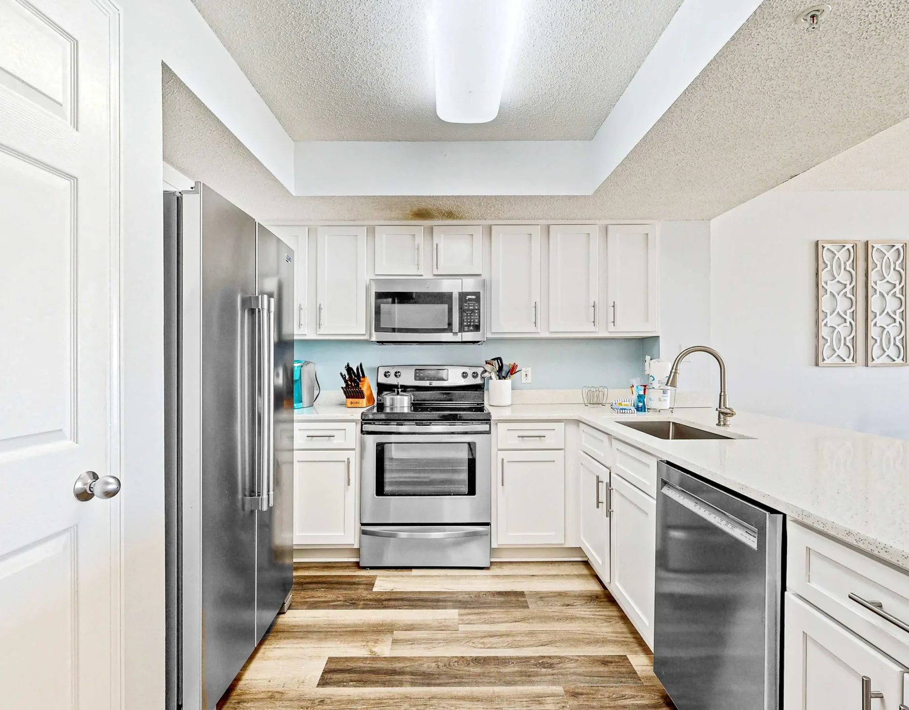 Una cocina luminosa con gabinetes blancos, electrodomésticos de acero inoxidable y un fregadero.