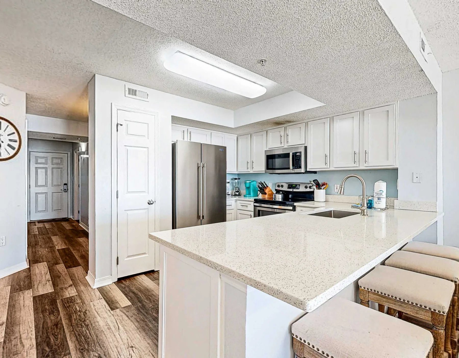 Una cocina luminosa con gabinetes blancos, electrodomésticos de acero inoxidable y una isla grande.
