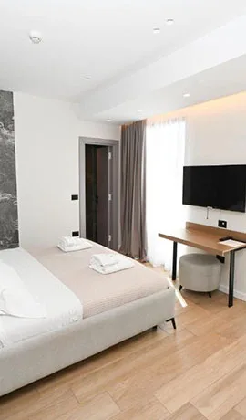 Espacio representativo del hotel: Un dormitorio de hotel luminoso con cama, escritorio y televisor en la pared.