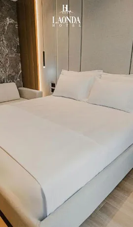 Espacio representativo del hotel: Una cama bien tendida está junto a una pared panelada en un dormitorio.