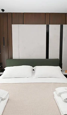 Espacio representativo del hotel: Un dormitorio de hotel con una cama bien arreglada y paneles de madera oscura.