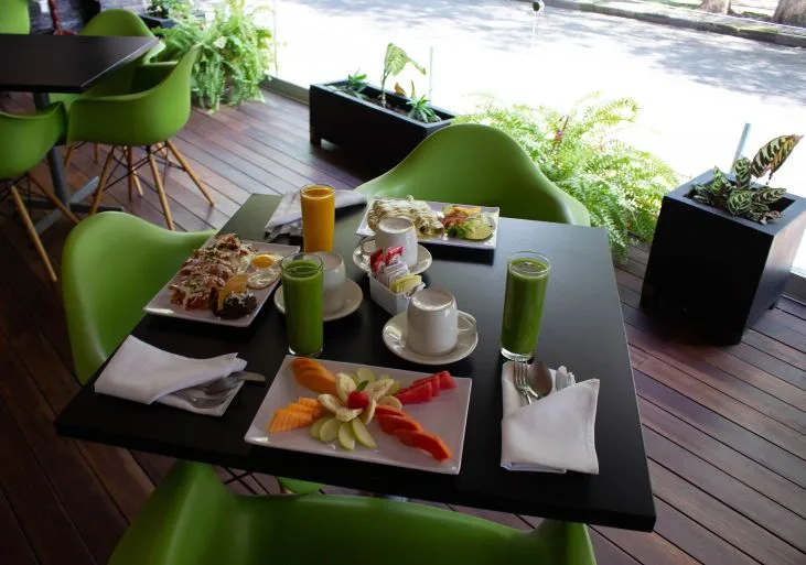 Representative hotel space: A dining table with plated food and drinks sits beside a bright window.