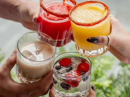 Representative hotel space: Several colorful drinks are held together for a toast.