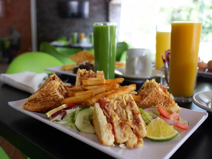 Representative hotel space: A dining table displays sandwiches, fries, salad, and glasses of juice.