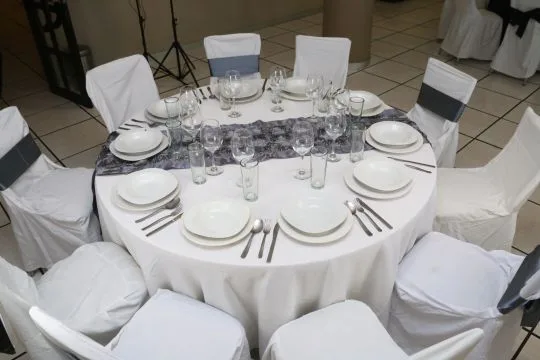 Representative hotel space: A round banquet table is set with plates, glasses, and white-covered chairs.