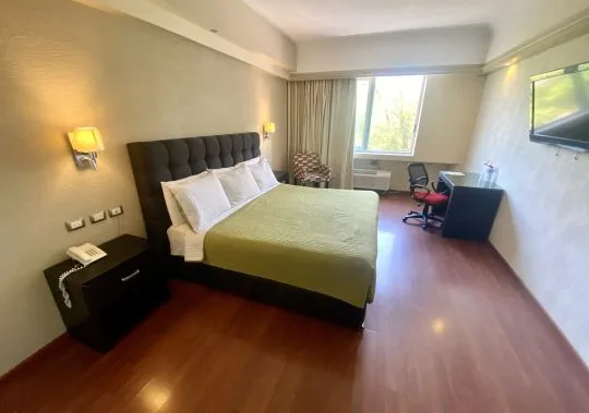 Representative hotel space: A bedroom with a bed, bedside table, and desk by the window.