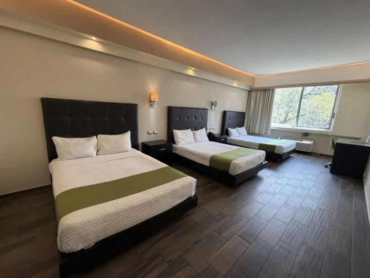 Representative hotel space: A bedroom with three beds and a large window.