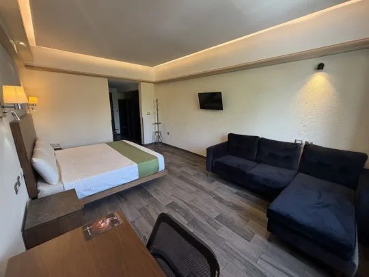 Representative hotel space: A hotel guest room with a bed and dark seating.