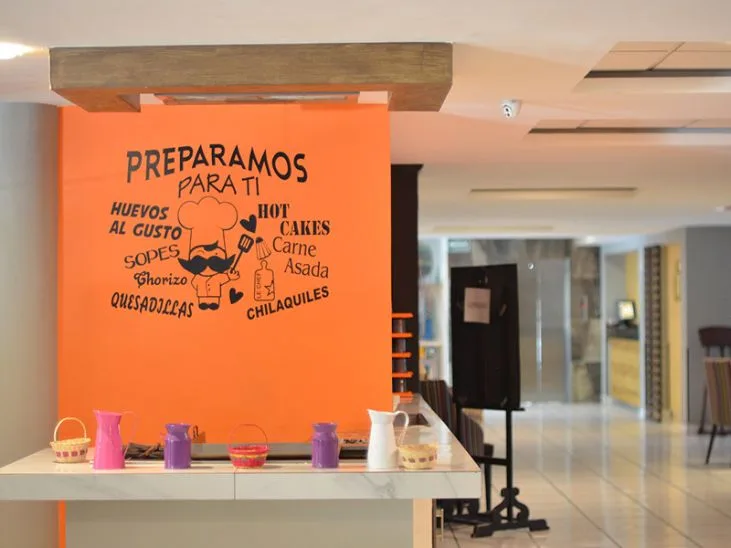 Representative hotel space: A hotel breakfast counter with a bright orange wall and food lettering.