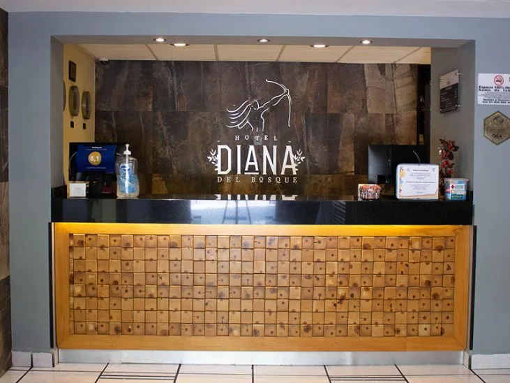 Representative hotel space: Hotel reception desk with a wooden front and a large wall logo.