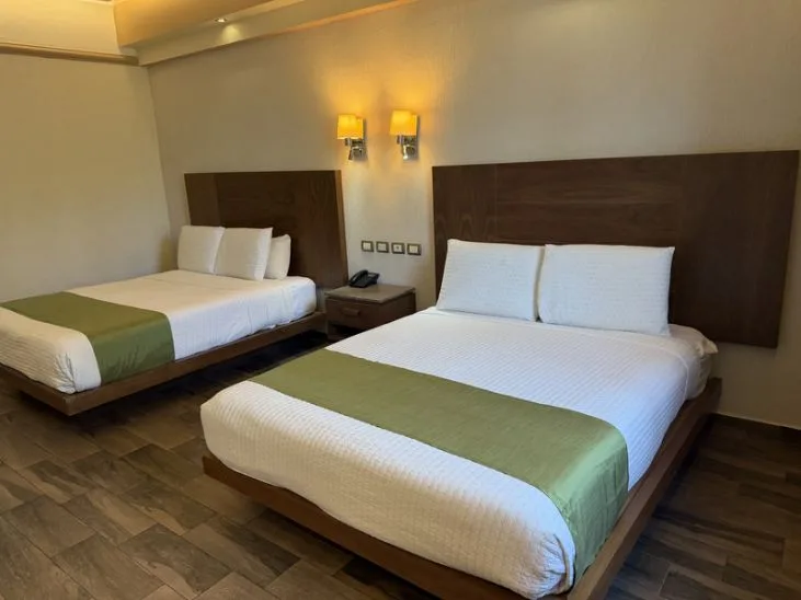 Representative hotel space: A hotel bedroom with two beds and matching green bed runners.