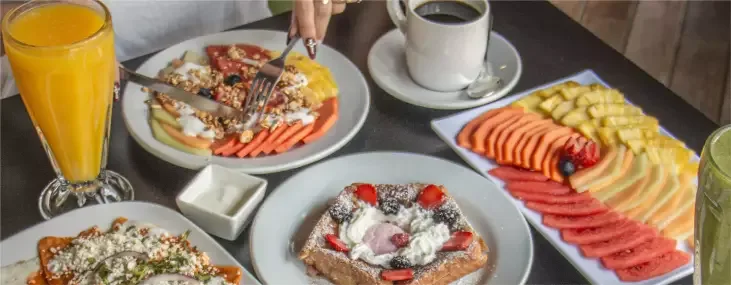 Representative hotel space: A breakfast spread with fruit, toast, juice, and coffee on a table.