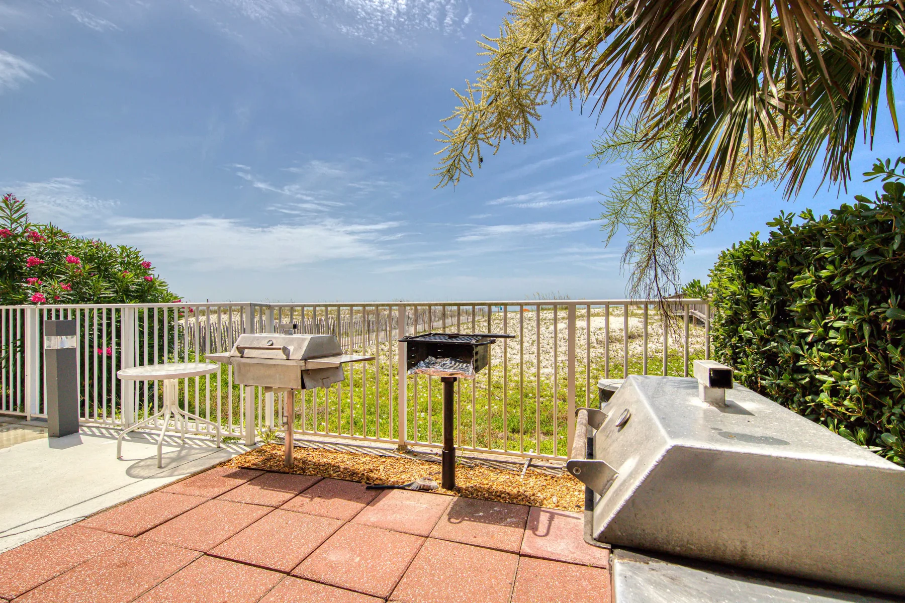Shared amenity: An outdoor patio with a railing, barbecue grill, and open sky.