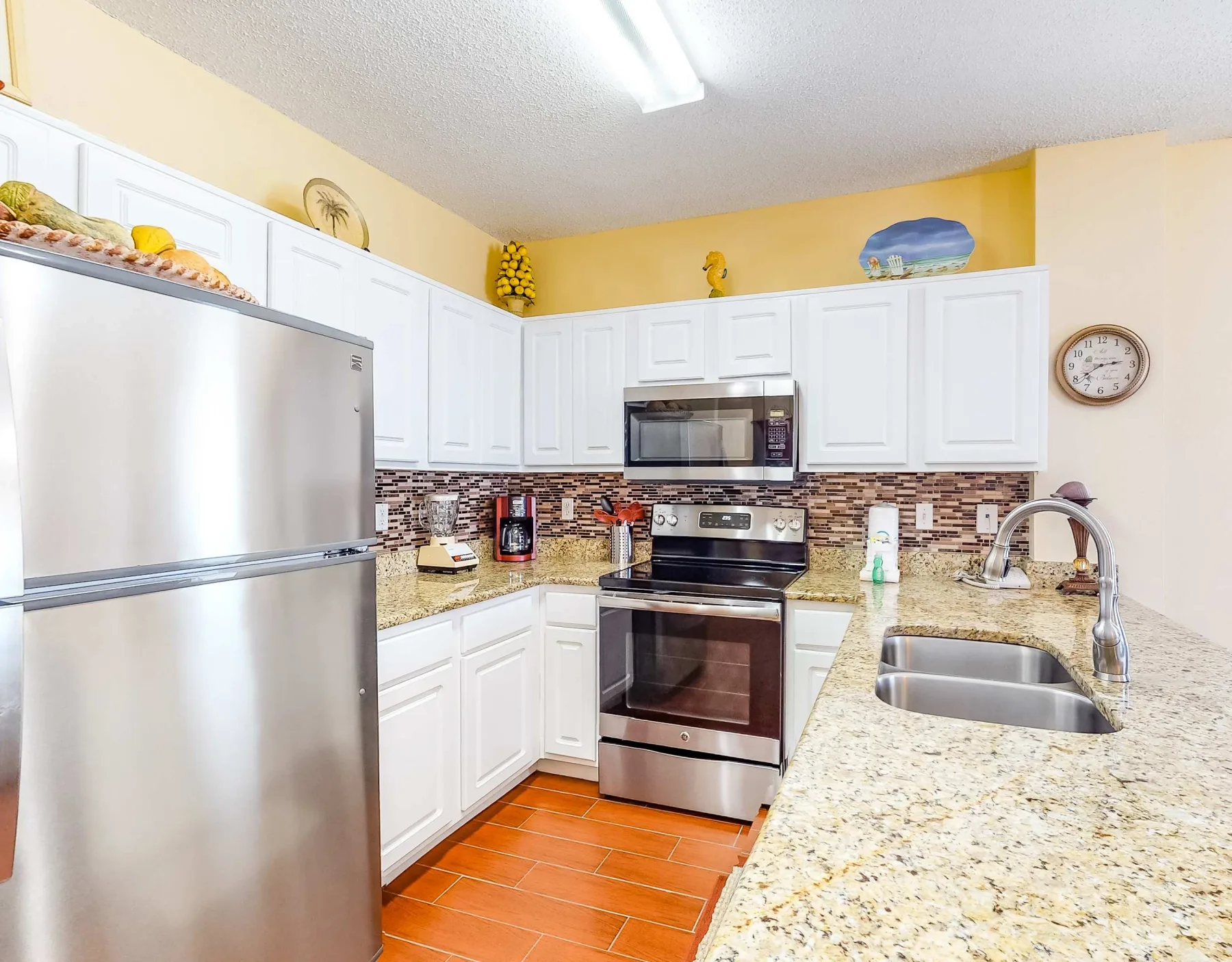 A bright kitchen with white cabinets, stainless steel appliances, and a countertop sink.