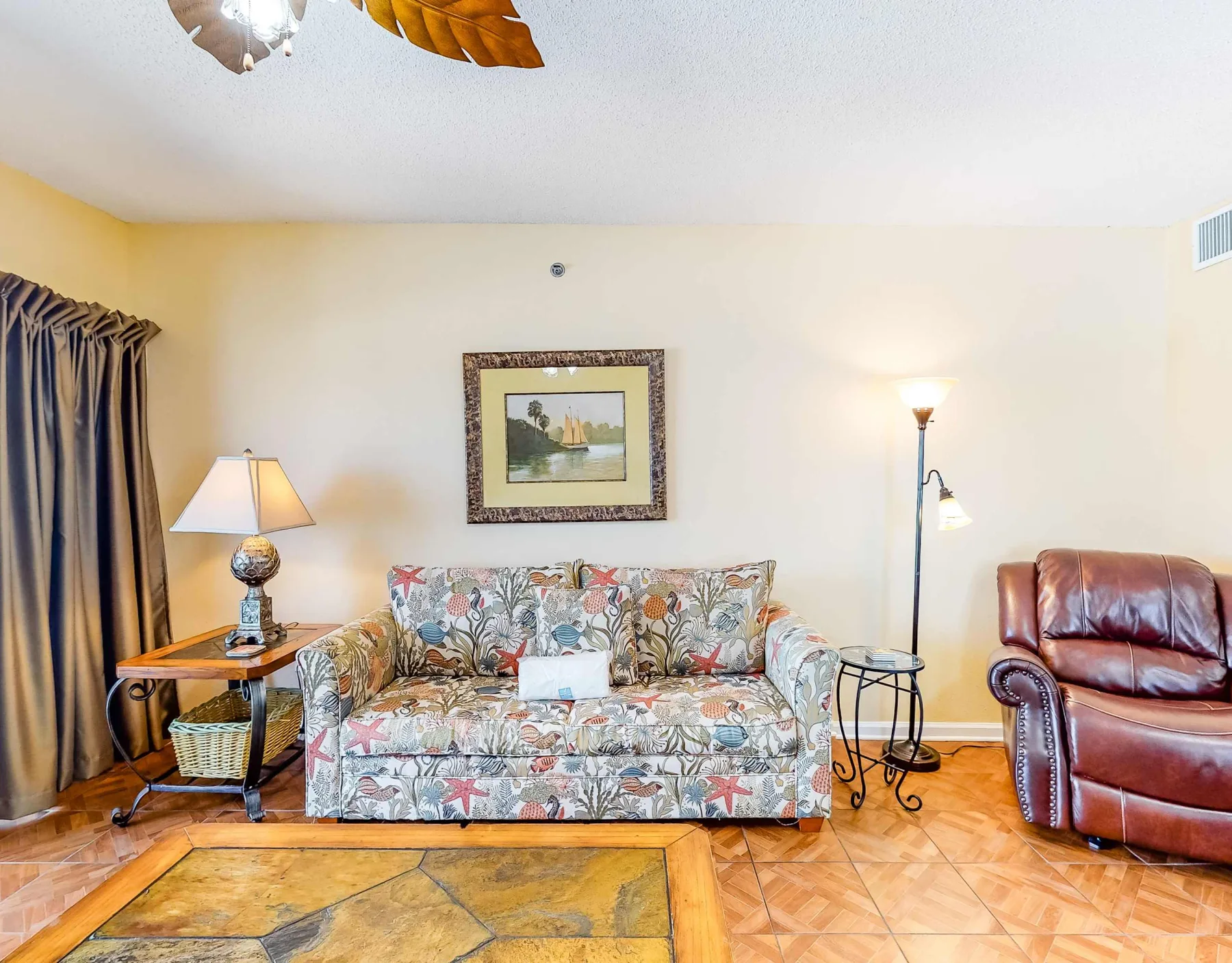 A living room with patterned seating, a leather armchair, and warm lighting.