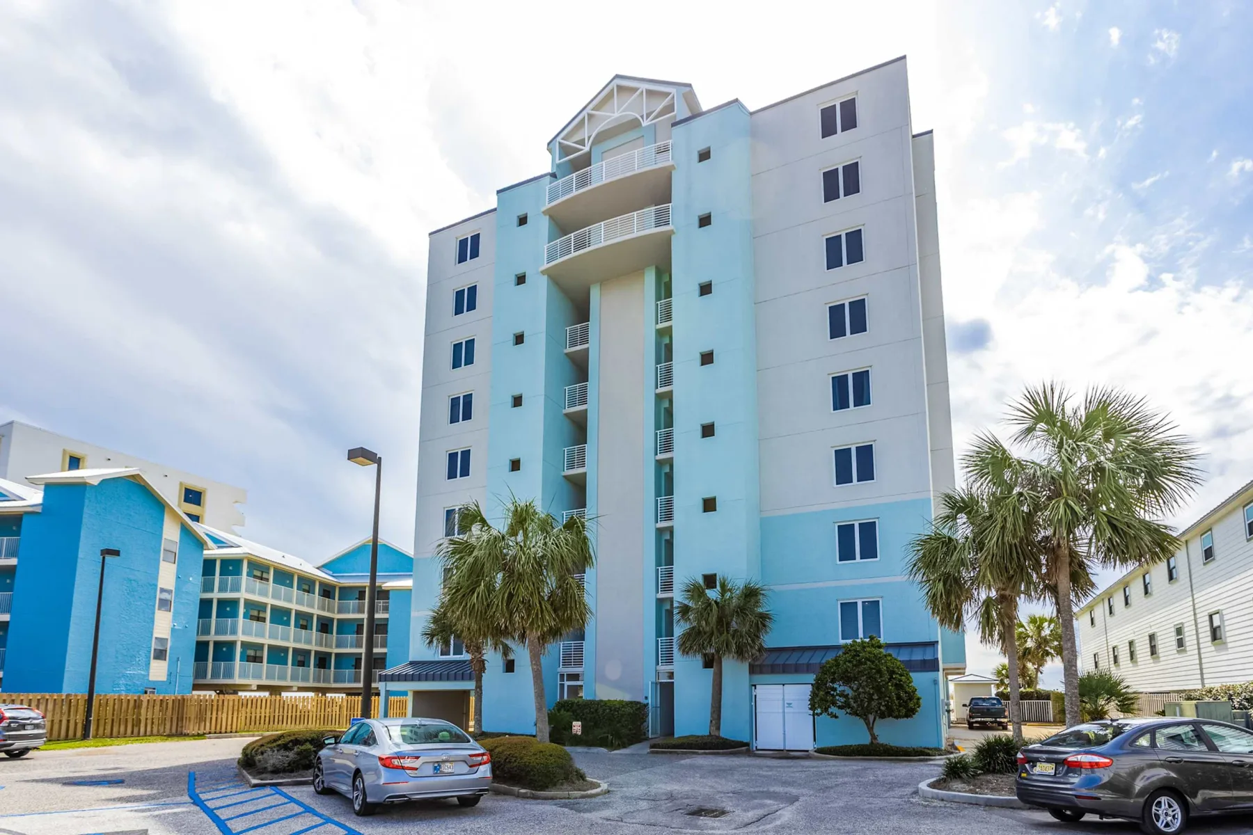 Shared amenity: A blue-and-white multi-story building stands beside a parking area.