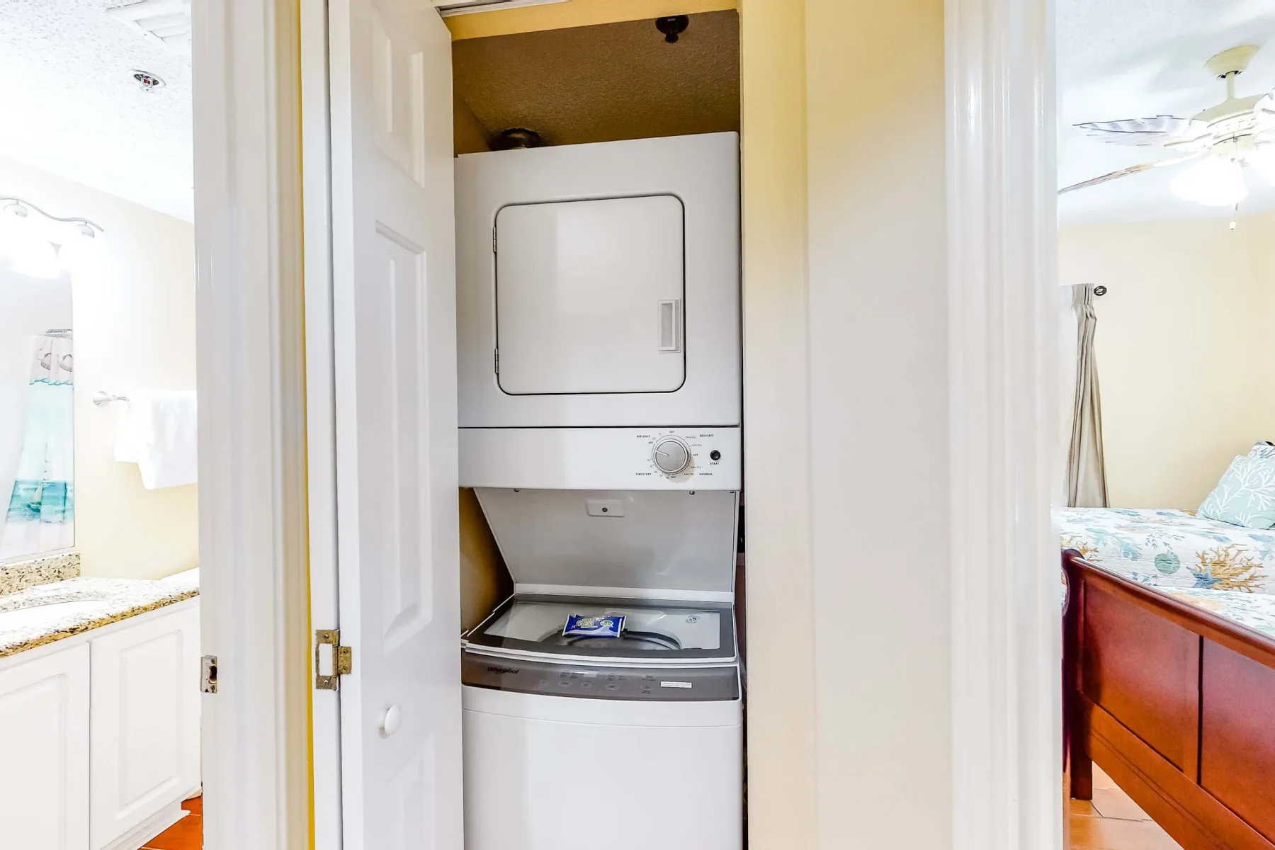 A stacked washer and dryer are set in a closet between two bedrooms.