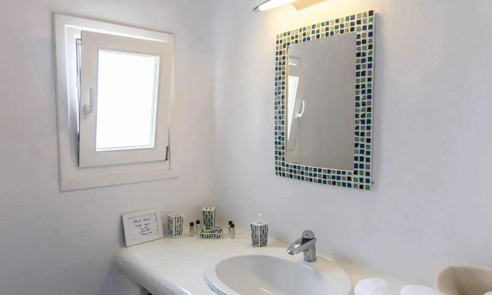 A bathroom vanity with a sink, mirror, and small window.