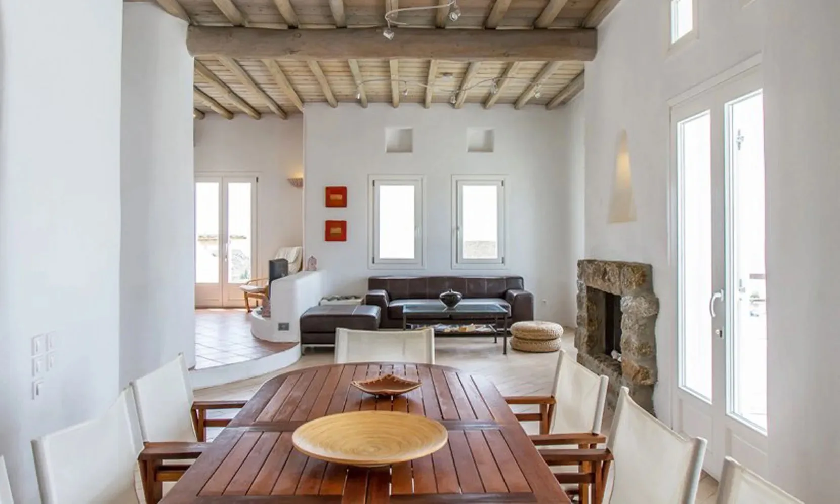 A bright dining and living area with a long wooden table and seating.