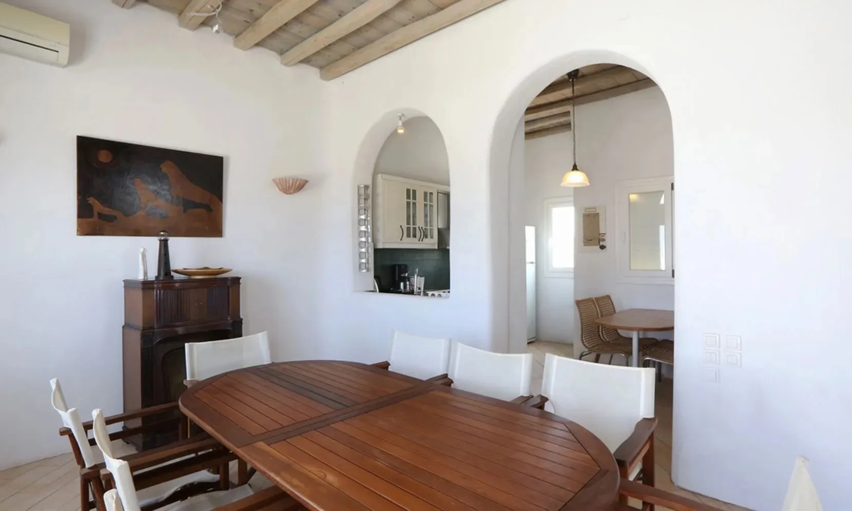 A dining area with a wooden table and chairs beneath exposed ceiling beams.