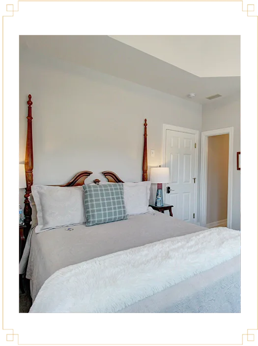 Representative hotel space: A bedroom with a large bed, pale bedding, and a bedside lamp.