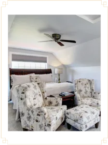 Representative hotel space: A bedroom seating area with floral armchairs beside a bed.