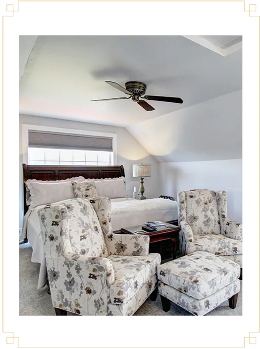 Representative hotel space: A bedroom with a bed, floral seating, and a ceiling fan.