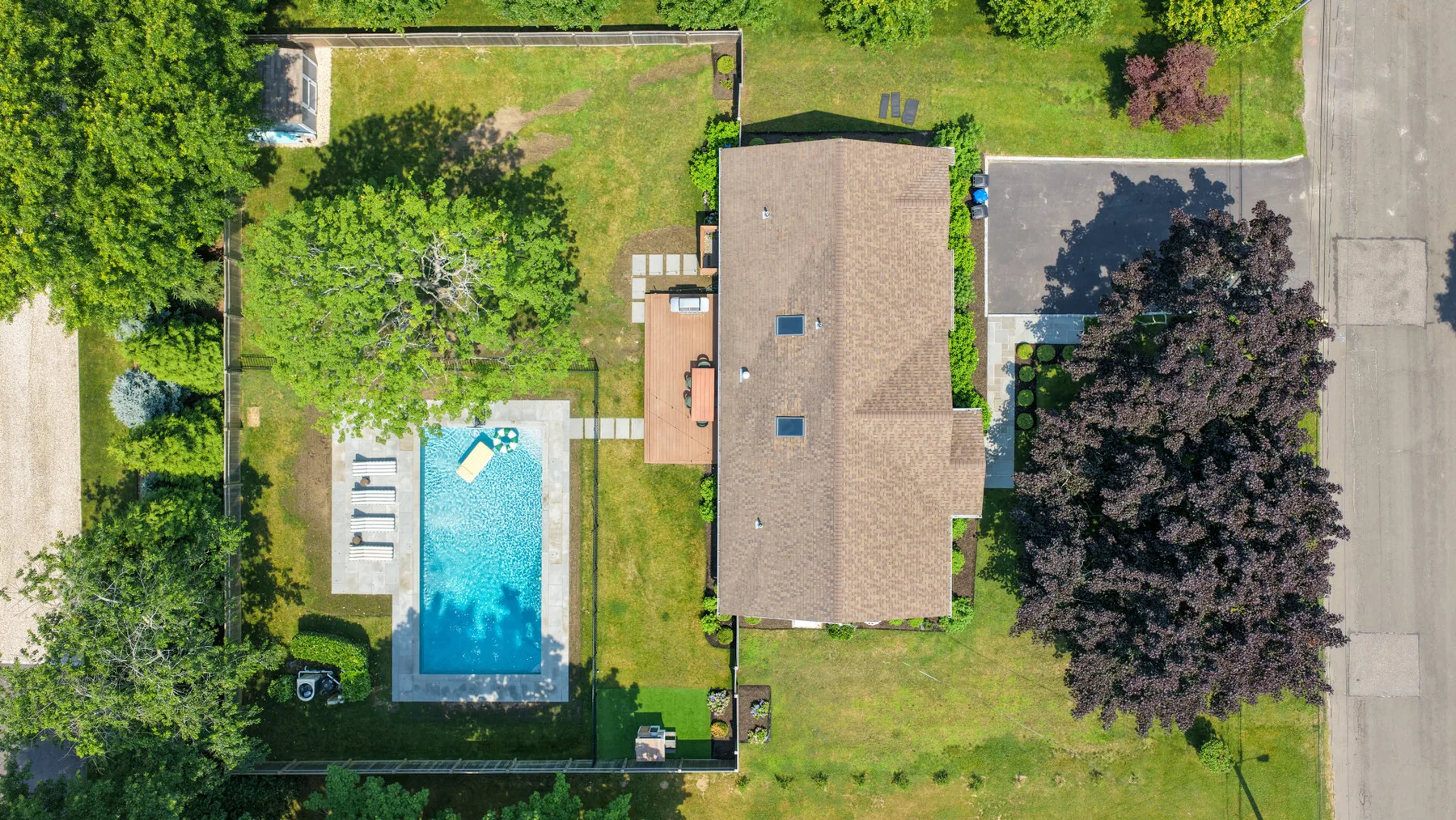 Una vista aérea muestra una casa junto a una piscina y un patio verde.