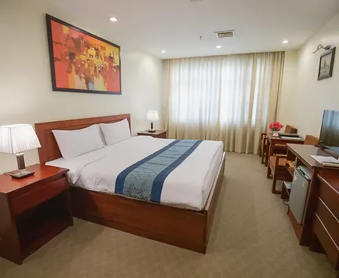 Representative hotel space: A bedroom with a large bed, bedside tables, and a curtained window.