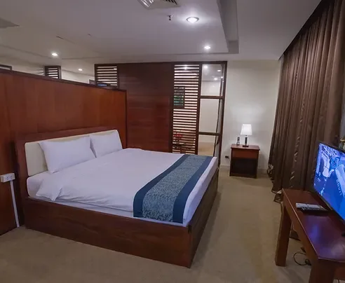 Representative hotel space: A bedroom with a bed, bedside table, and television.