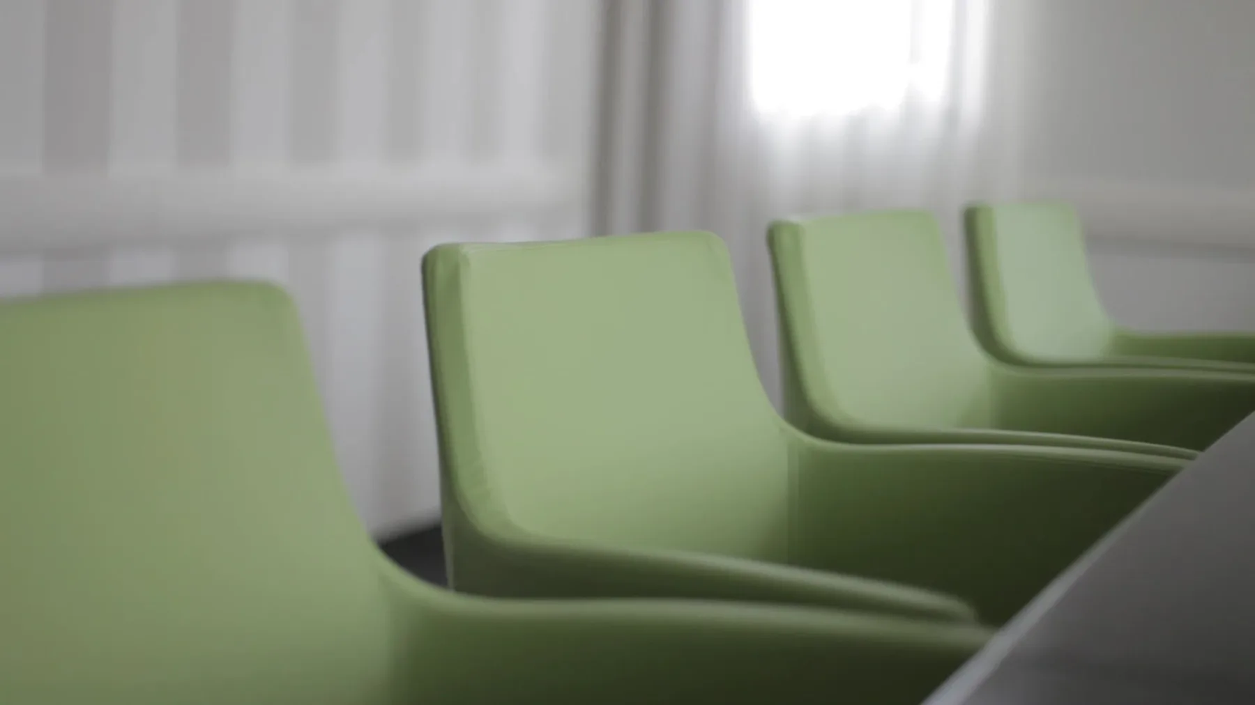 Representative hotel space: A row of green seating is arranged beside a bright window.