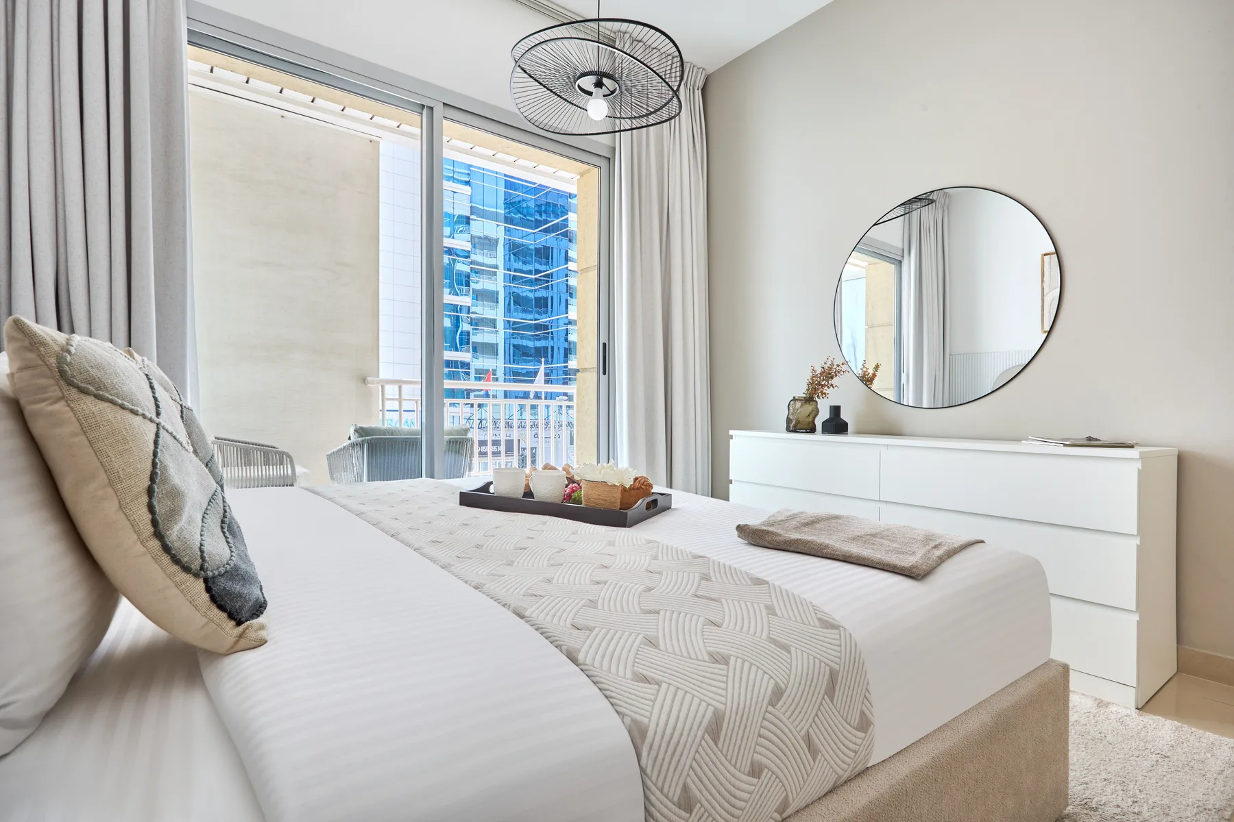 Un dormitorio luminoso con una cama bien hecha junto a una ventana grande.
