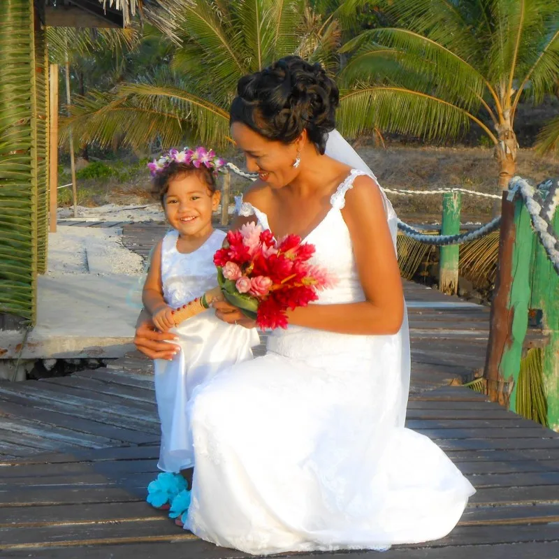 Espacio representativo del hotel: Una novia y una niña posan juntas en un camino de madera entre palmeras.