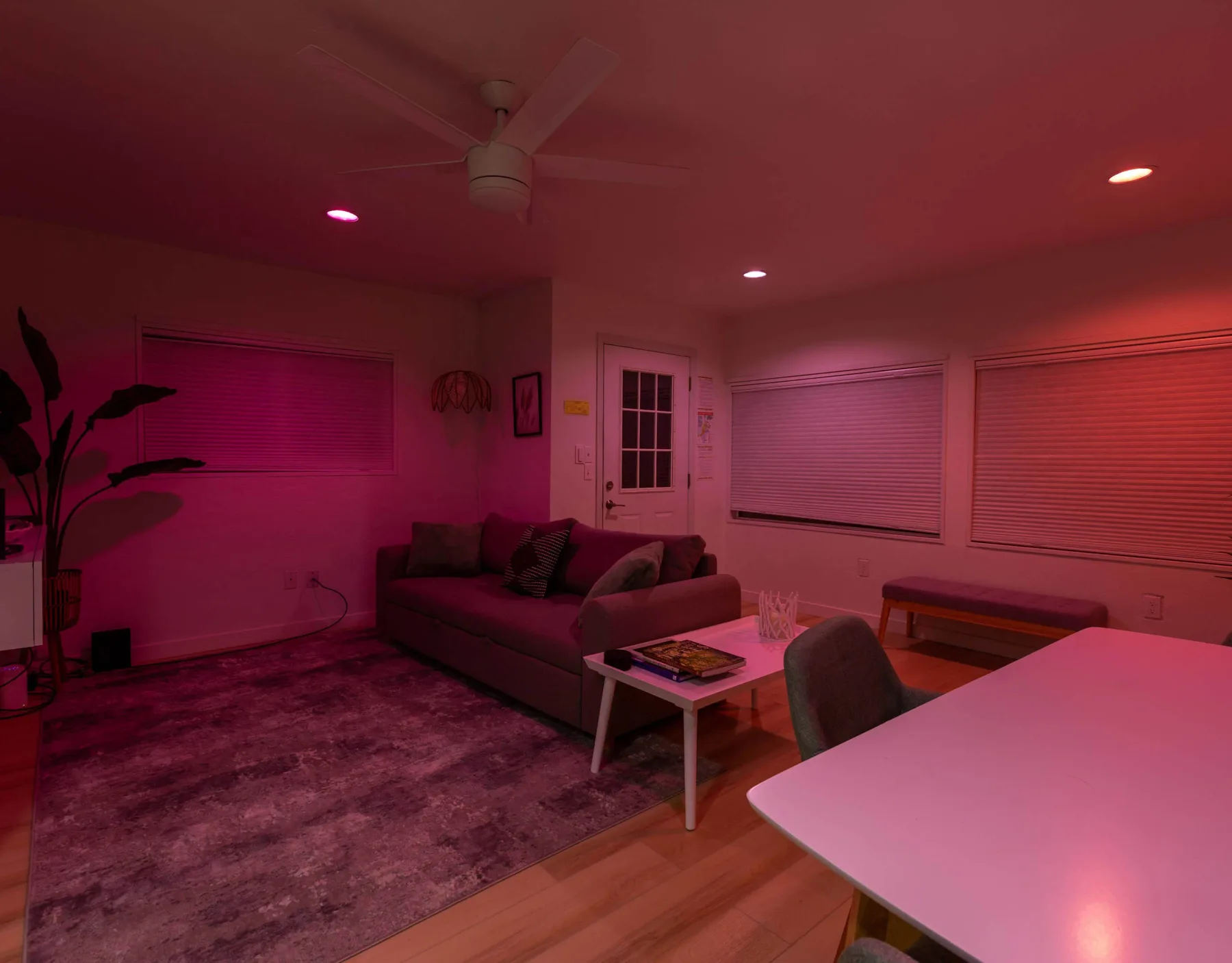 A living room with seating around a coffee table and several large windows.