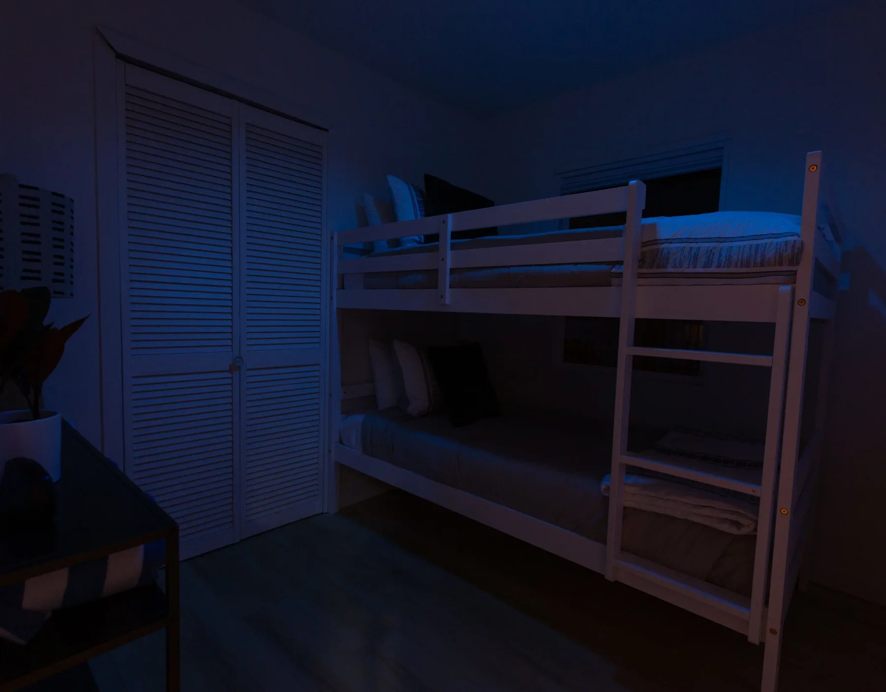 A dim bedroom with a bunk bed and louvered closet doors.